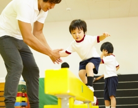 子どもが先生と一緒に跳び箱をしている写真